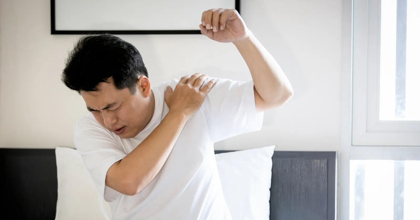 Homme se tenant l'épaule douloureuse, bras levé