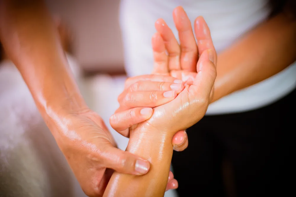 Mains examinant et massant la main d’un patient